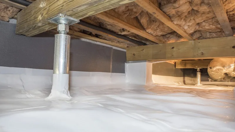 Crawl space liner run across the soil, sealed around a support pier and carried up the foundation wall